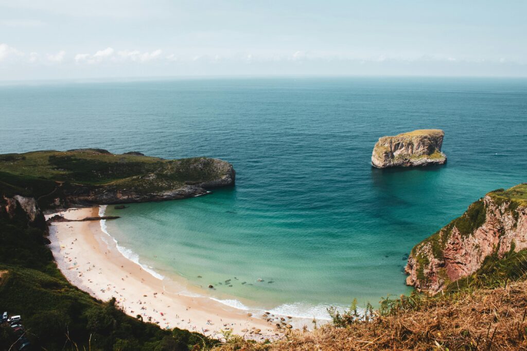 A stunning aerial shot of a secluded beach and sea stack in Asturias, Spain.