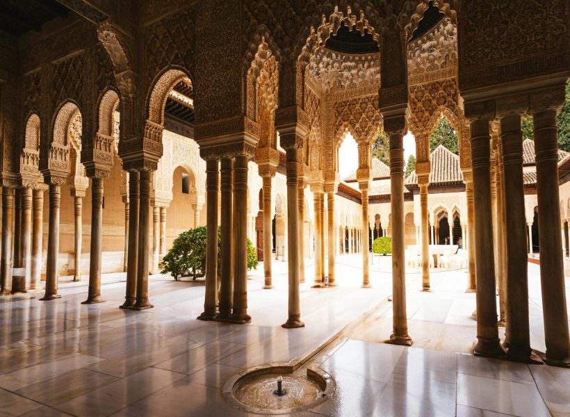 Experience the intricate arches and columns of Alhambra's stunning courtyard in Granada.