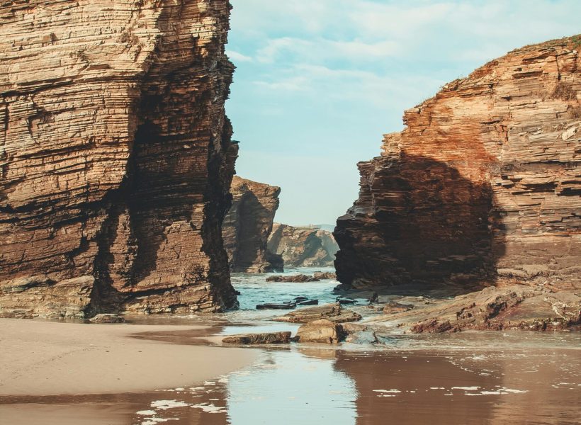 Majestic rocky cliffs at low tide revealing unique geological formations on a tranquil beach.